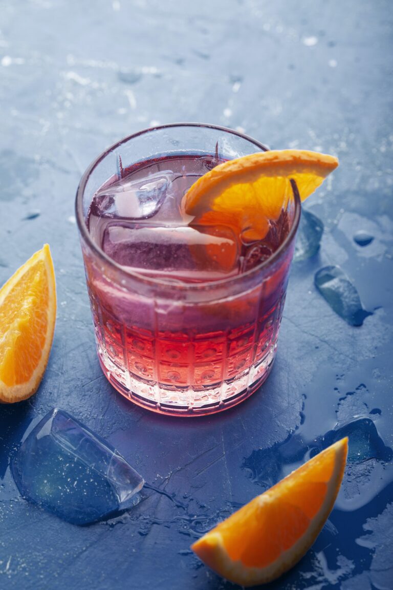 Fresh ice tea summer cocktail with orange and ice. Background toned in modern blue color 2020